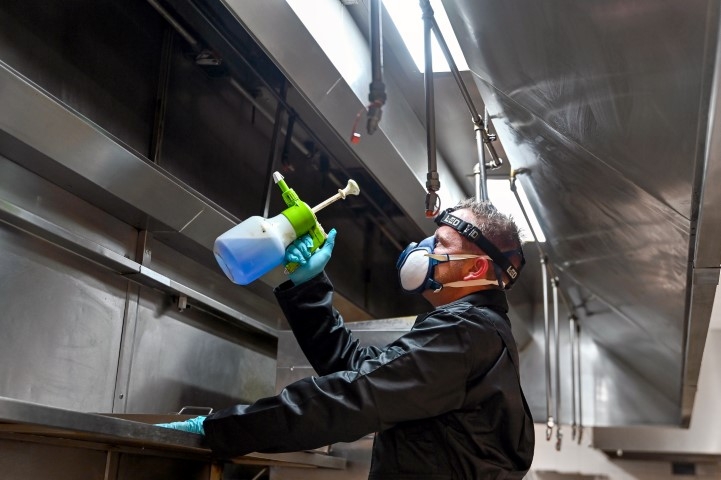 Employee wearing a mask, holding cleaning solution